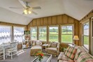 The welcoming sun room boasts comfortable furnishings, a flat-screen TV and natural light flooding from wall-to-wall windows.