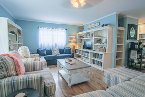 The living room of this vacation home features overstuffed sofa seating with bright, beachy-colored pillows.