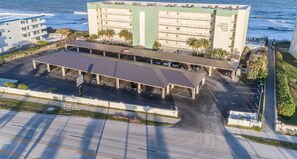 Aerial view of the beachfront condo complex, showcasing covered parking and breathtaking ocean scenery.