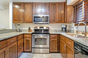 Fully equipped kitchen with stainless appliances and granite countertops, open to living and dining.