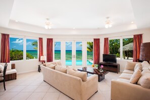 The living room features a TV and stunning ocean views.