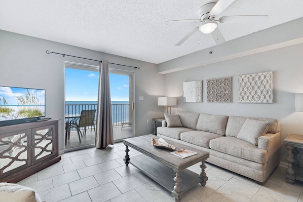 Living area with sofa sleeper, flat screened TV, and beautiful neutral decor with access to the Gulf-front balcony.