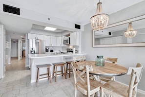 Dining area with seating for four at the table and four stools at the breakfast bar of the fully equipped kitchen.