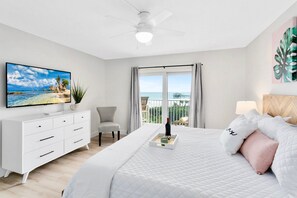 Spacious master bedroom with a plush king bed, flat-screen TV, and private balcony access.