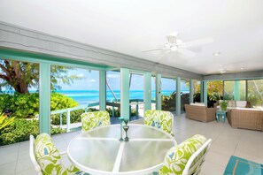 The screened porch comes furnished with a dining table and lounge area with sweeping ocean views.