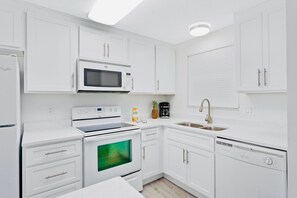All-white kitchen featuring new cabinetry, appliances, and a bright, clean design for an enjoyable cooking experience.