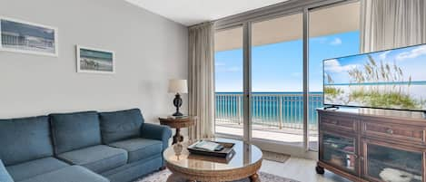 Living room area with a sleeper sofa, flat screen TV, and balcony access with beautiful Gulf views!