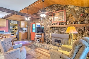 The main living area has hardwood flooring & a half-wall stone hearth fireplace.