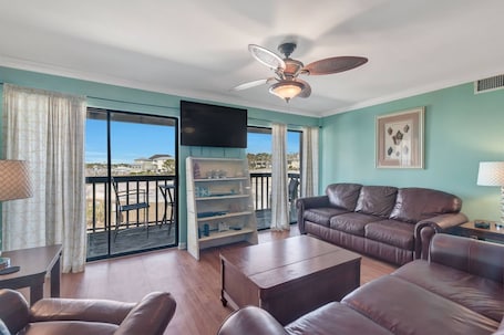 Living area with a plenty of seating (and a sofa sleeper!) with wall mounted TV and balcony access.