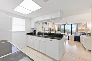 Modern kitchen with sleek white cabinetry, black countertops, and an open floor plan.