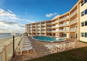 Relax by the beachfront pool, surrounded by comfortable lounge chairs and serene ocean views.