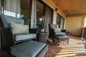 Tastefully decorated balcony seating area with matching chairs & ottomans