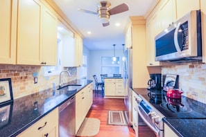 The kitchen features stainless steel appliances, a tiled backsplash and hardwood floors.