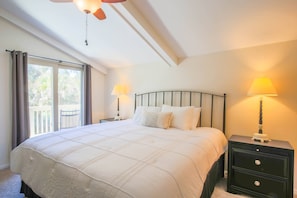 The master bedroom features a king bed, nightstands with reading lamps and sliding door access to the outdoor balcony.