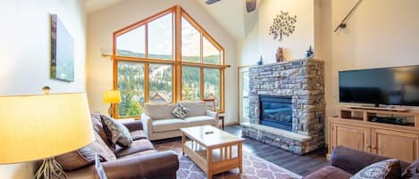 Living area featuring hardwood flooring, vaulted ceilings, ample seating, gas fireplace, flat screen TV and access to the private balcony.