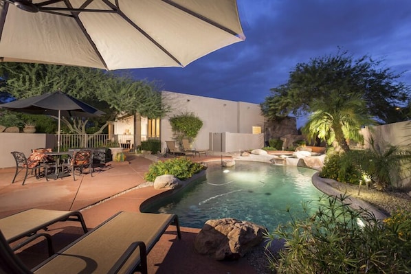 The pool area has four chaise lounge chairs and a table with four chairs. There are three umbrellas for added shade in the pool area.