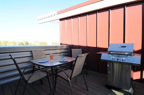 A BBQ and dining set on the roof top deck.