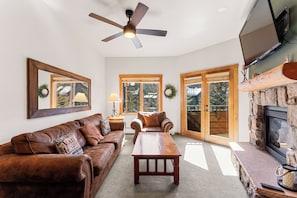 Living area with a mounted TV over a gas fireplace, queen sleeper sofa, and access to the private balcony.
