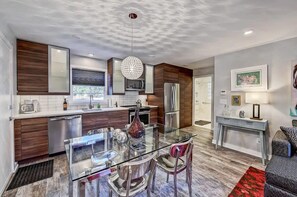 Updated kitchen area with modern appliances and an elegant glass dining table