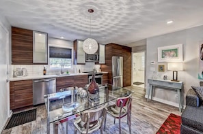Updated kitchen area with modern appliances and an elegant glass dining table