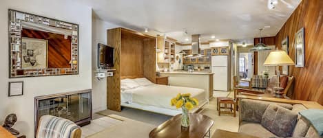 View from front entry over living room, queen Murphy bed, kitchen, eating area and hallway leading you to the bedroom with private deck.