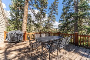 Main balcony featuring a outdoor dining area, gas grill, and mountain views.