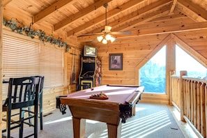 The spacious upstairs game room - The game room on the top floor, beneath the towering cathedral ceiling, features a pool table, an arcade, a TV, and a cozy bar table, making it perfect for whiling away a rainy day.