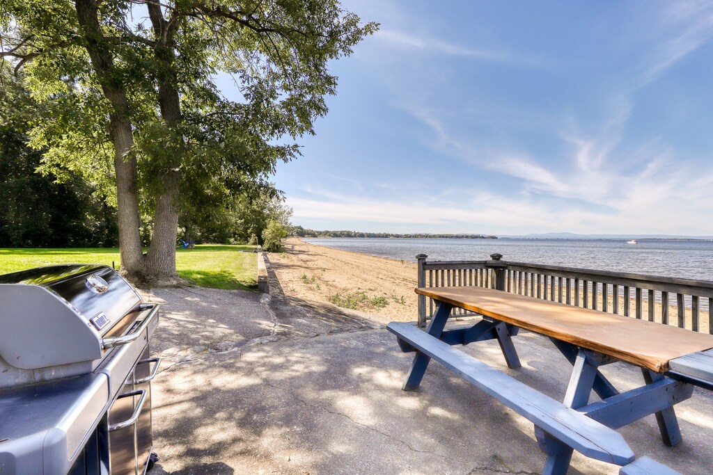 A picnic table and a grill by a beach at a Vermont vacation rental