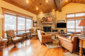 Cozy Main Level Living Room with Comfortable Seating, TV, and Warm Fireplace Surrounded by Mountain Views