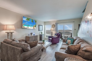 Enjoy watching the big game on the 65in Smart TV in the living area with the natural light shinning in