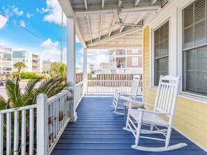 Lower porch with rocking chair seating that's ideal for enjoying the beach breeze