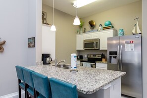 Fully equipped kitchen with stainless steel appliances and breakfast bar for four