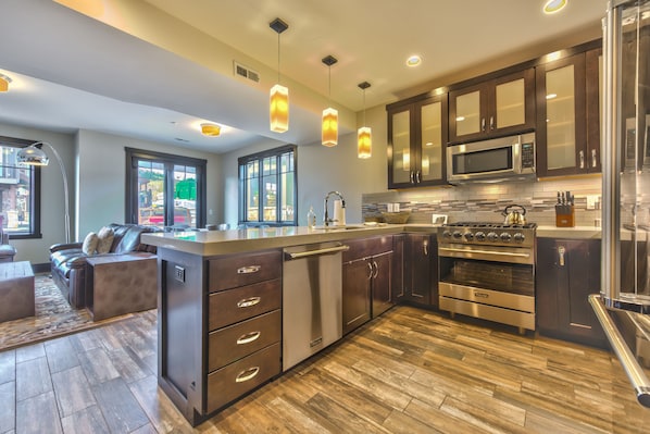 Fully Equipped Kitchen with Stainless Steel Appliances, a 6-Burner Viking Gas Range, Granite Countertops, Bar Seating for 4, Dining Area, and a Comfortable Living Room
