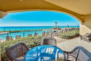 Patio with outdoor dining table and comfy chairs at Adagio B102 - Watch the children swim while you relax in this freshly updated gulf front pool from your Friend at The Beach.