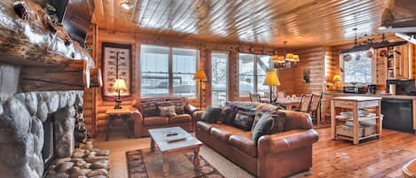Log Cabin Design Condo with Great Room featuring a Living Room with a Stone Fireplace, Fully Equipped Kitchen, Dining Area, Hardwood Floors, and Private Deck