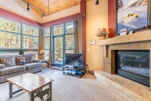 Living area featuring vaulted ceilings, gas fireplace, flat screen TV and access to the balcony.