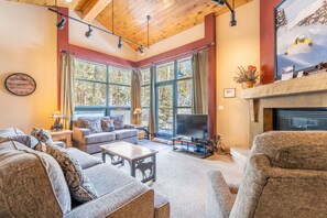 Living area featuring vaulted ceilings, gas fireplace, flat screen TV and access to the balcony.