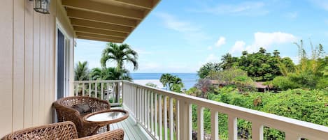 The upper lanai of this Kona Hawai'i vacation rental with wicker chairs and ocean views.