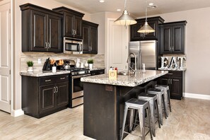 Kitchen View - The Kitchen is fully stocked with all the dishes, cookware, baking pans, and cutlery you will need for meal preparations and includes stainless steel appliances and granite counter tops.