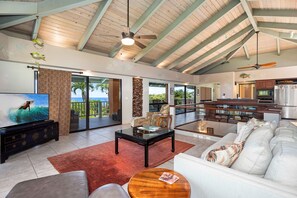 The expansive upstairs living area has soaring wood beamed ceilings, indirect lighting, ocean views