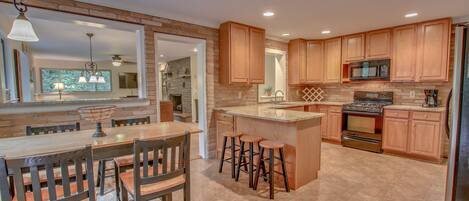 Kitchen with Microwave, Refrigerator, Table, Chairs, Stools, and Bar Counter.