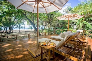 Relax on the deck  and pool on the beach, surrounded by palm trees and wildlife.