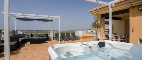 View of the large terrace from the jacuzzi, with a solarium and dining area.