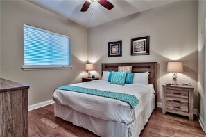 Master bedroom with king bed, ceiling fan, dual nightstands and lamps and beach decor
