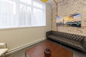Leather couch, brick wall living area with nice big windows