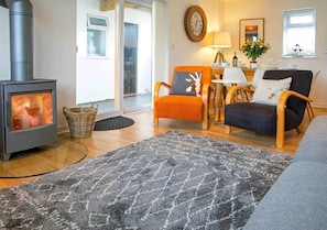 The main living area has comfy seating, a woodburner and patio doors providing access to the garden