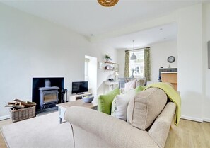 Comfy sofas surround an attractive feature fireplace with wood burning stove, perfect for cosy evenings at any time of year