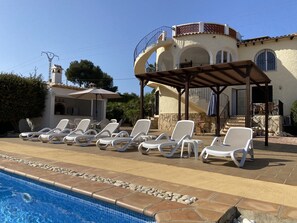 Confortable sunbeds and external pool bar/kitchen with pergola