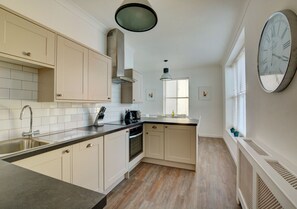 Kitchen with electric oven and hob, dishwasher, combination microwave, fridge with icebox, freezer, washer/dryer, dining table and chairs