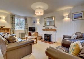 The stylish living /dining room has comfy leather sofas and a welcoming wood burning stove